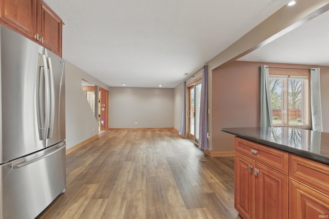 kitchen with freestanding refrigerator, light wood finished floors, baseboards, brown cabinetry, and recessed lighting