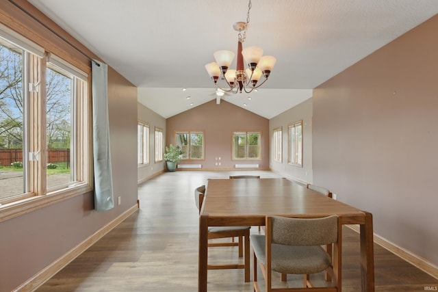 dining area with plenty of natural light, a chandelier, wood finished floors, lofted ceiling, and baseboards