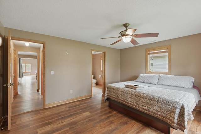 bedroom featuring wood finished floors, baseboards, and connected bathroom