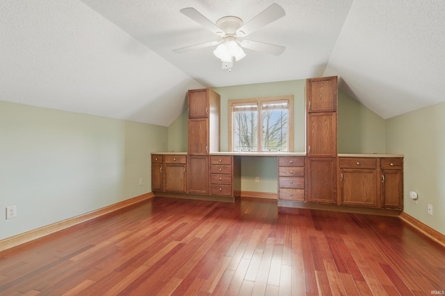 additional living space with lofted ceiling, dark wood finished floors, ceiling fan, and baseboards
