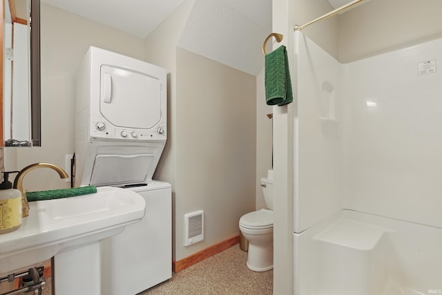 full bath featuring estacked washer and dryer, a shower, baseboards, and toilet