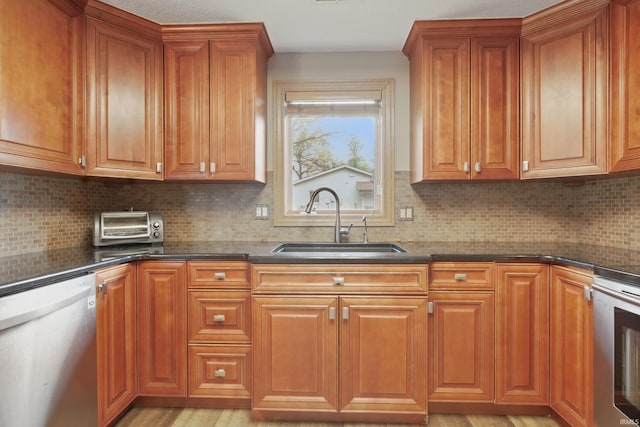 kitchen with dishwashing machine, a sink, range, brown cabinetry, and tasteful backsplash