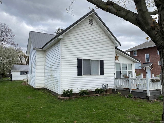rear view of house featuring a deck, a yard, and metal roof