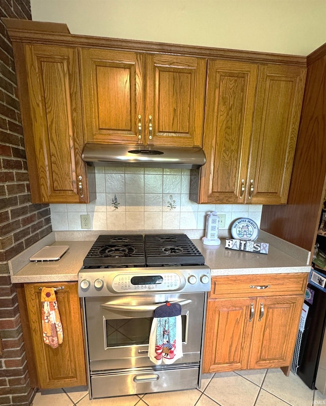 10059 Quince Rd, Plymouth, IN 46563 - kitchen with gas range, brown cabinetry, light countertops, under cabinet range hood, and brick wall