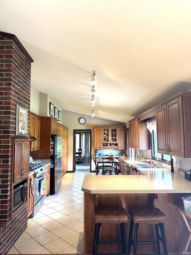 10059 Quince Rd, Plymouth, IN 46563 - kitchen featuring appliances with stainless steel finishes, light tile patterned floors, a peninsula, a breakfast bar area, and light countertops