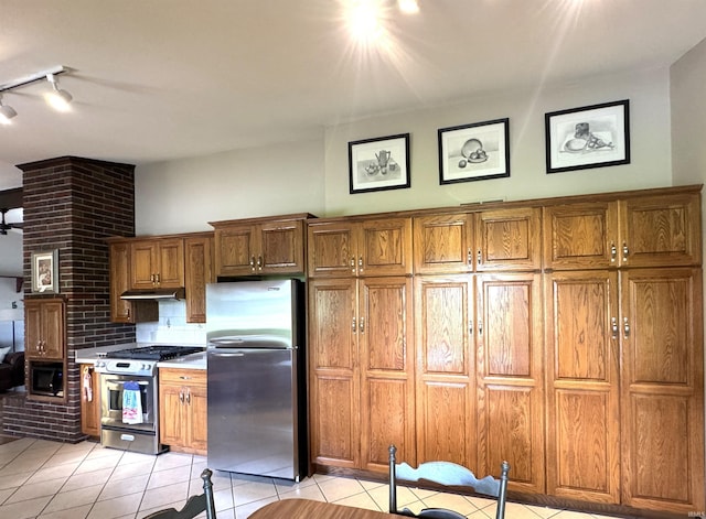 10059 Quince Rd, Plymouth, IN 46563 - kitchen featuring appliances with stainless steel finishes, under cabinet range hood, light tile patterned flooring, track lighting, and brown cabinetry