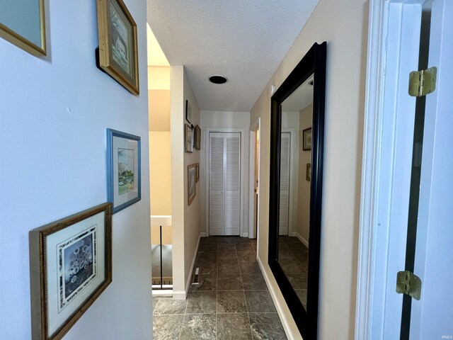 corridor featuring baseboards and a textured ceiling