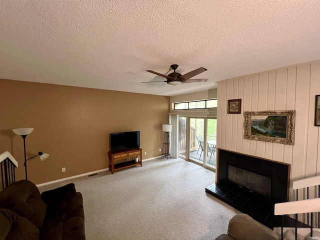 carpeted living room featuring ceiling fan, baseboards, a textured ceiling, and a fireplace