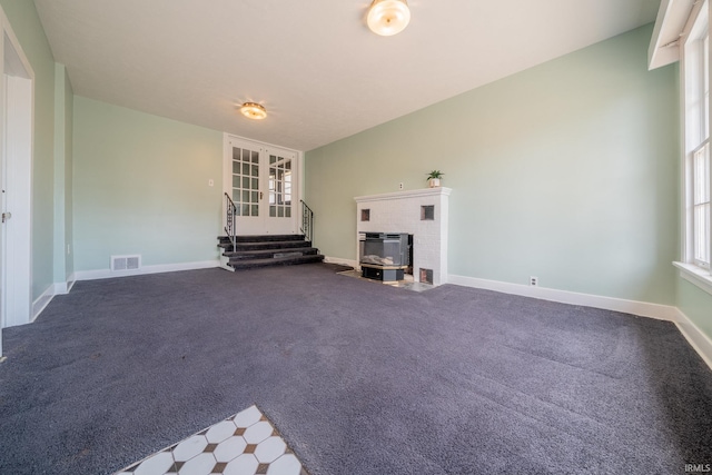 unfurnished living room with a brick fireplace, baseboards, and carpet