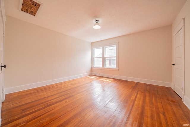 spare room featuring baseboards and light wood finished floors