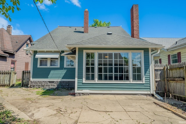 rear view of house with a patio, fence, and a chimney