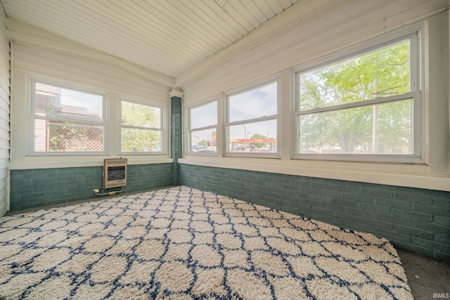 unfurnished sunroom with healthy amount of natural light, vaulted ceiling, and heating unit