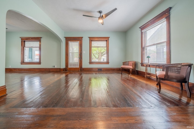 living area featuring hardwood / wood-style flooring, a ceiling fan, plenty of natural light, and arched walkways