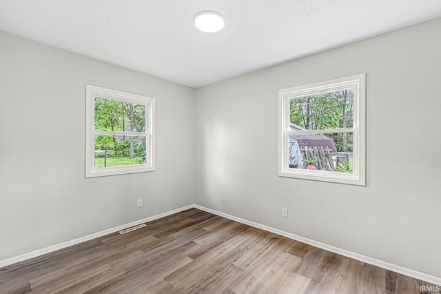 spare room with healthy amount of natural light, wood finished floors, and baseboards