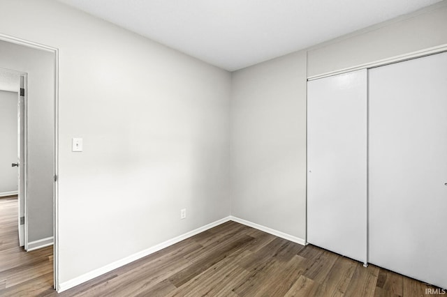 unfurnished bedroom featuring wood finished floors, a closet, and baseboards