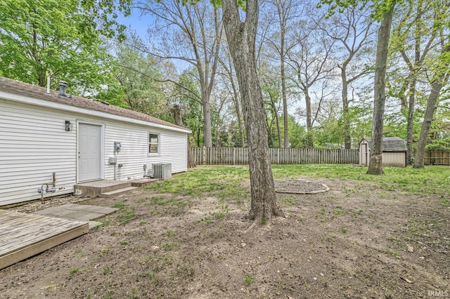 fenced backyard with central air condition unit, an outbuilding, and a shed