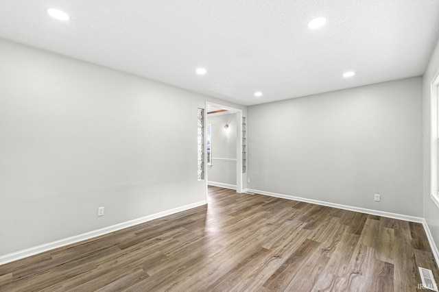 spare room with recessed lighting, wood finished floors, and baseboards