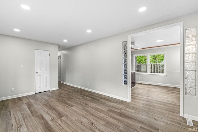 unfurnished room featuring baseboards, wood finished floors, and recessed lighting