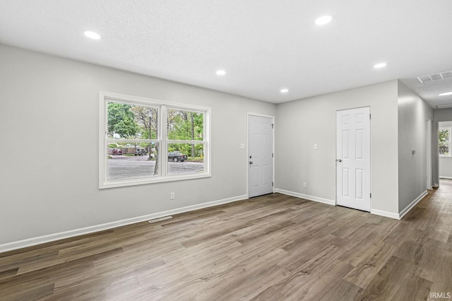 unfurnished living room featuring recessed lighting, wood finished floors, and baseboards