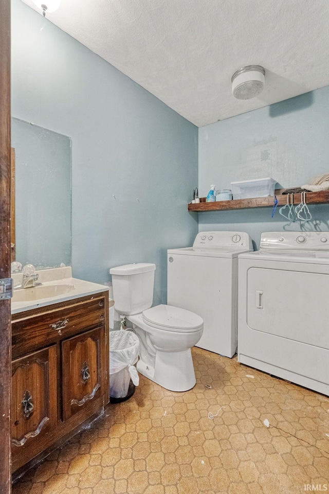 bathroom featuring separate washer and dryer, toilet, tile patterned floors, vanity, and a textured ceiling