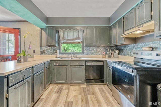 kitchen featuring stainless steel electric range, black dishwasher, a sink, under cabinet range hood, and a peninsula