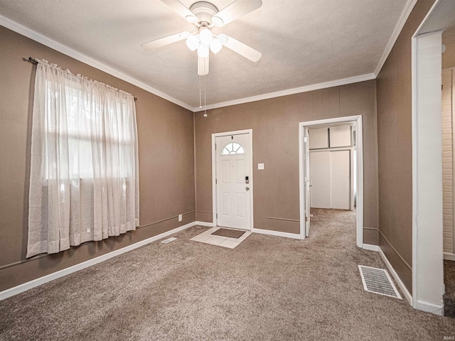 foyer featuring healthy amount of natural light, carpet flooring, a ceiling fan, ornamental molding, and baseboards