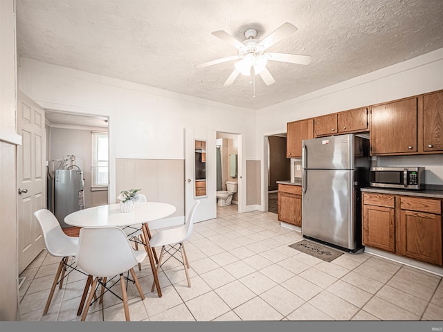 kitchen with appliances with stainless steel finishes, brown cabinetry, a textured ceiling, a ceiling fan, and water heater