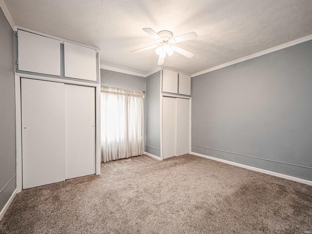 unfurnished bedroom featuring crown molding, light carpet, two closets, and ceiling fan