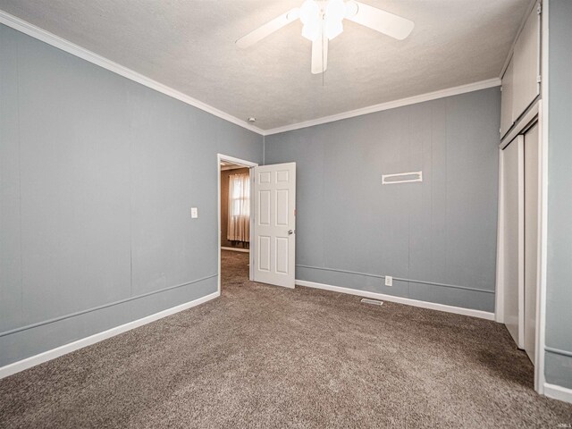 unfurnished bedroom featuring carpet flooring, crown molding, a closet, a ceiling fan, and baseboards