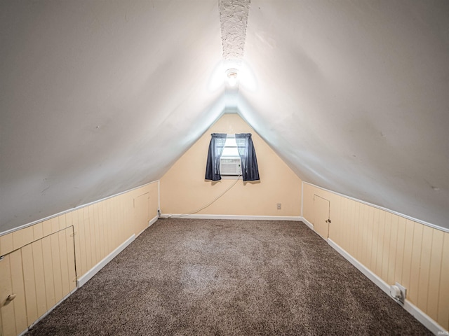 additional living space featuring vaulted ceiling, wooden walls, carpet floors, cooling unit, and baseboards