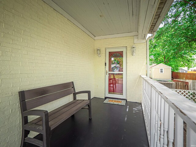 doorway to property featuring brick siding and fence