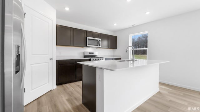 8180 Carlie Ct, Fort Wayne, IN 46818 - kitchen featuring stainless steel appliances, light wood-style flooring, a center island with sink, dark brown cabinets, and recessed lighting