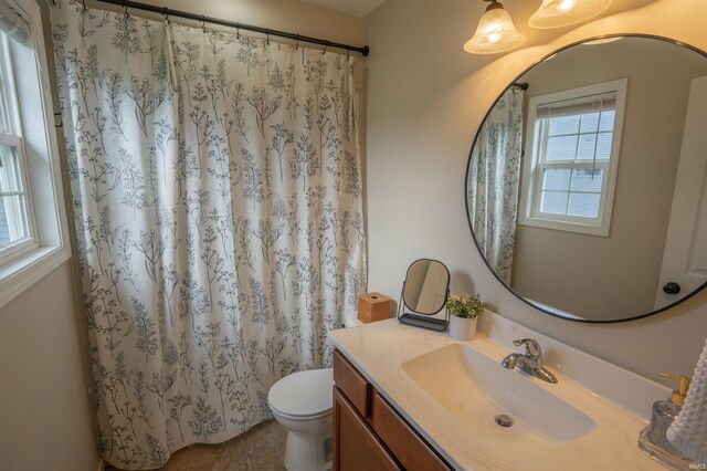 bathroom featuring toilet, vanity, and curtained shower