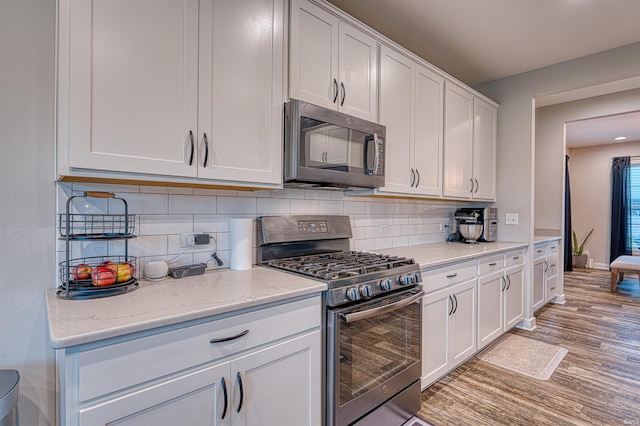 5783 Brookstone Dr, Newburgh, IN 47630 - kitchen with stainless steel appliances, white cabinets, light wood finished floors, and decorative backsplash