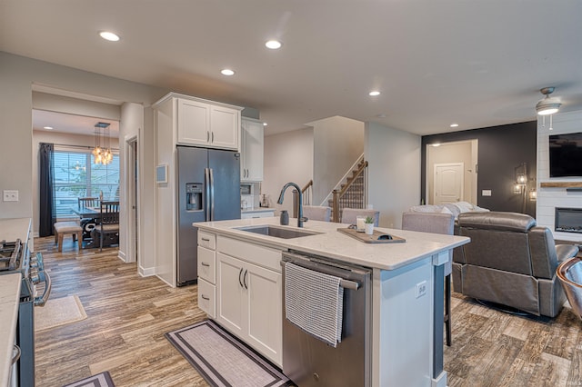 5783 Brookstone Dr, Newburgh, IN 47630 - kitchen featuring appliances with stainless steel finishes, a sink, open floor plan, white cabinetry, and light wood-style floors