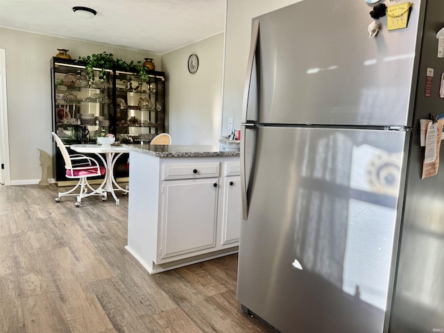 1719 Linwood Dr, Bedford, IN 47421 - kitchen featuring freestanding refrigerator, wood finished floors, white cabinetry, light stone countertops, and a peninsula