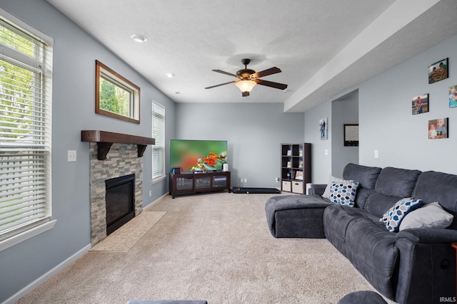 carpeted living area with a ceiling fan, baseboards, a stone fireplace, and recessed lighting