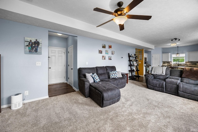 carpeted living area featuring a textured ceiling, a ceiling fan, and baseboards