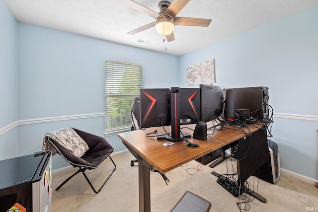 carpeted office space featuring baseboards and a ceiling fan