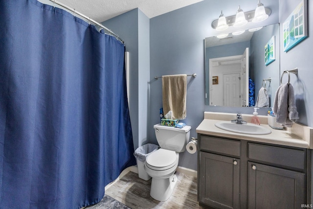 full bath featuring toilet, wood finished floors, vanity, a textured ceiling, and curtained shower
