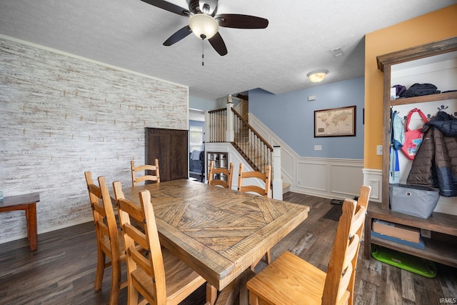 dining area featuring a ceiling fan, stairs, a wainscoted wall, wood finished floors, and a textured ceiling