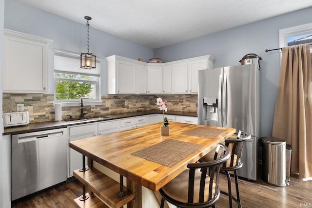 kitchen featuring appliances with stainless steel finishes, a sink, dark countertops, and decorative backsplash