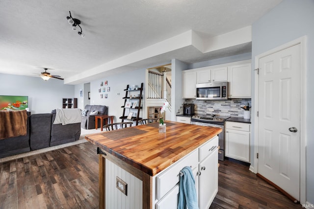 kitchen featuring appliances with stainless steel finishes, white cabinetry, butcher block counters, tasteful backsplash, and a textured ceiling