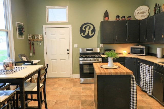 1008 E Walnut St, Petersburg, IN 47567 - kitchen featuring appliances with stainless steel finishes, wood counters, dark cabinets, a high ceiling, and a kitchen island