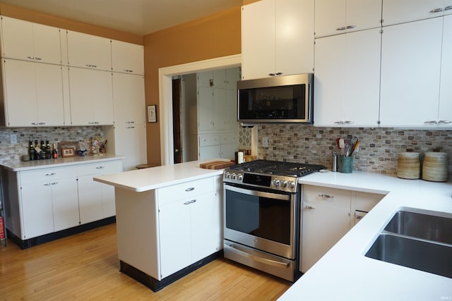 1208 Leeper Ave, South Bend, IN 46617 - kitchen featuring appliances with stainless steel finishes, a peninsula, light countertops, backsplash, and light wood-style floors