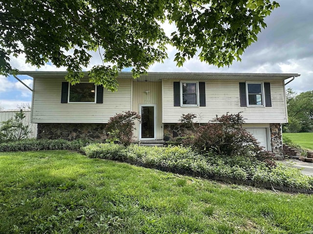 raised ranch with stone siding, a garage, and a front yard