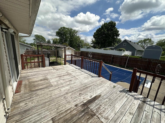 wooden deck featuring a fenced backyard, a storage unit, and an outdoor structure