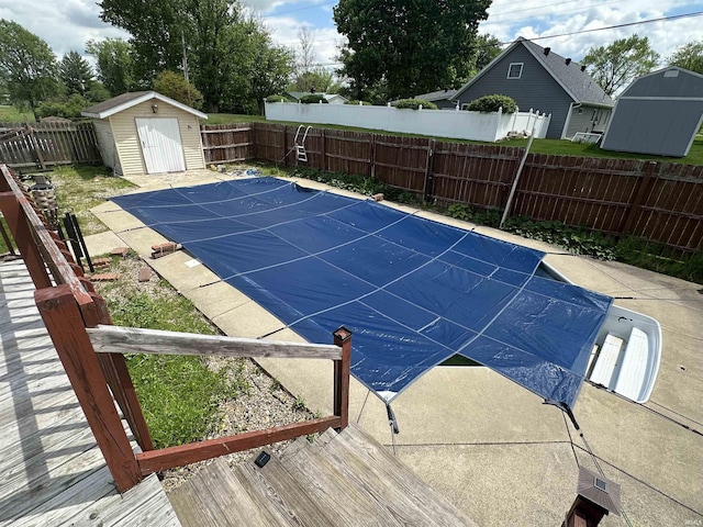 view of swimming pool with a storage unit, a fenced backyard, and an outbuilding