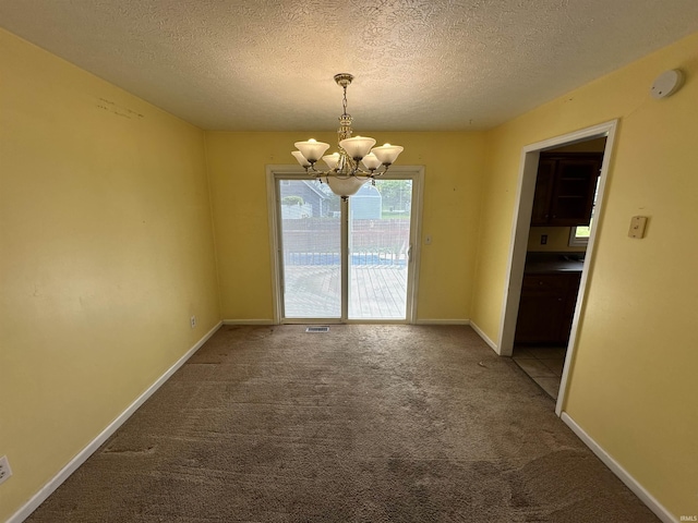 spare room featuring a chandelier, carpet flooring, a textured ceiling, and baseboards