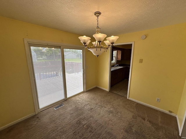 unfurnished dining area featuring a chandelier, carpet floors, a textured ceiling, baseboards, and a sink